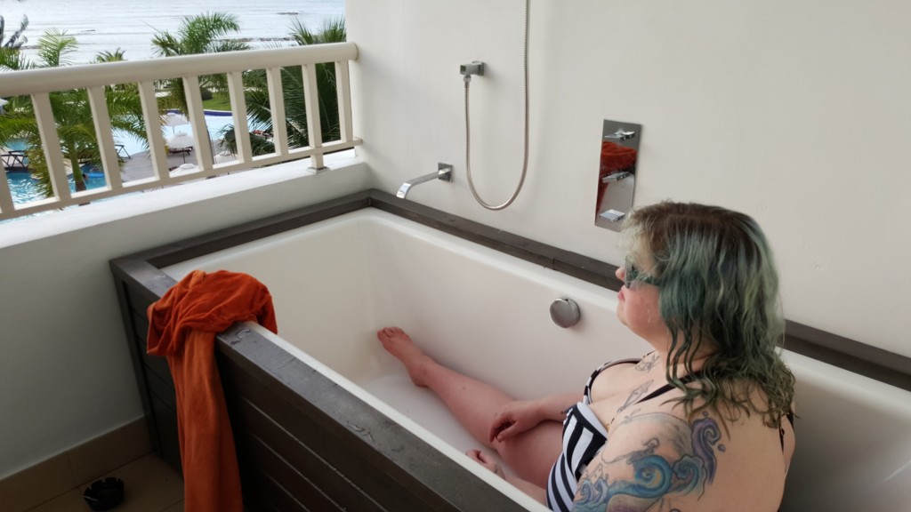 Me, in a black and white striped swimsuit, sitting in a bathtub on the balcony, staring  blankly out at the ocean.  There is no water in the bathtub.