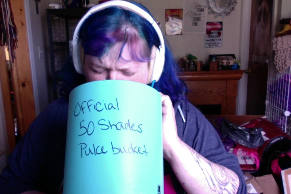 Me, miming barfing into a wastebasket I've sloppily written "Official 50 Shades Puke Bucket" on in black Sharpie.