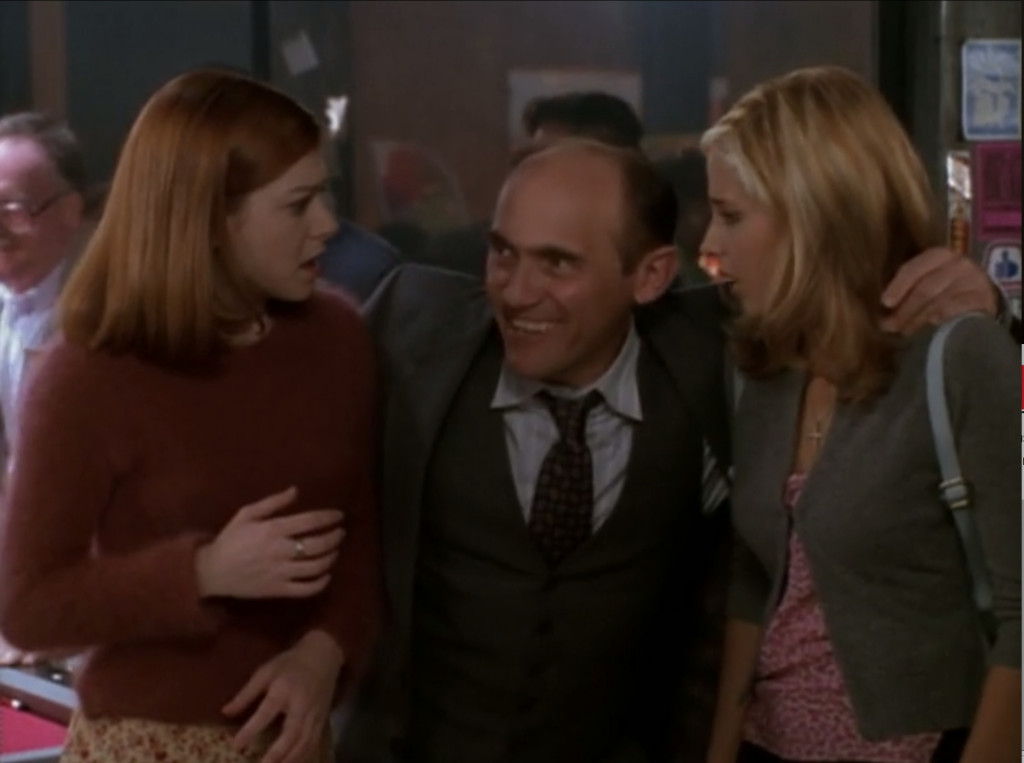 Snyder is standing between Buffy and Willow with his arms hanging around their shoulders like they're old pals.