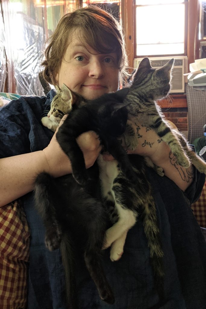me, with messy hair, holding three kittens up to my face